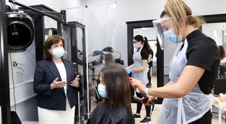 Minister Dodds with hairdressing students in hair salon at Bangor Campus